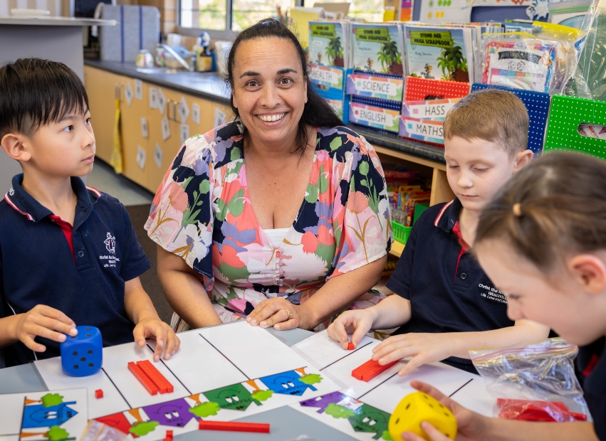 Christ the King School teacher Kim Fannin, centre, smiles at the camera. She has students on either side of her.